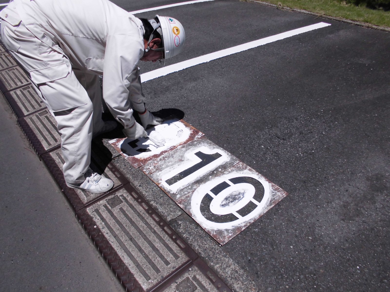 型板を使って駐車区画の番号を施工している様子
